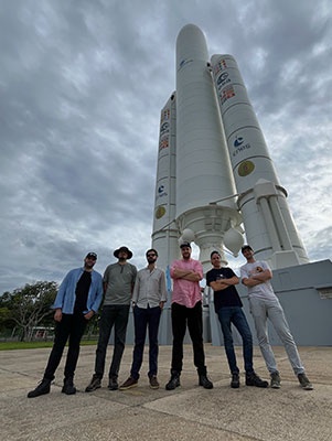 Tres dels estudiants de l'equip del NanoSat Lab van participar al port espacial europeu de Kourou, a la Guaiana francesa, en la integració final a l'Ariane 6. A la foto, jutament amb l'altre equip espanyol, Adrián Pérez-Portero (amb la camisa rosa),  seguit d'esquerra a dreta per Luis Contreras i Guillem Gràcia i Solà, davant la maquesta d'un coet europeu.