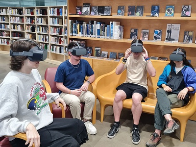 Parte del equipo de estudiantes que han participado en la producción del vídeo, experimentando con las gafas de realidad virtual, en la Biblioteca Rector Gabriel Ferraté, en Barcelona